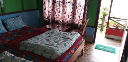 a bedroom with a bed and a table and a window at Vamoose Rigzen in Pedong