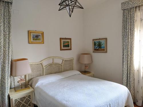 um quarto com uma cama branca e duas mesas com candeeiros em Attico Panoramico Vista Mare em Anzio