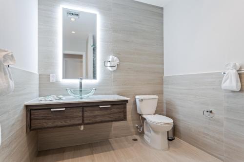 a bathroom with a sink and a toilet and a mirror at Sunset Caribe Belize in San Pedro