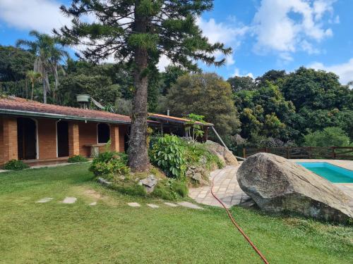 a house with a tree next to a pool at Chácara Mata Fria Com Piscina Aquecida in Mairiporã