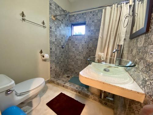 La salle de bains est pourvue d'un lavabo en verre et d'une douche. dans l'établissement Aj Mun, Hotel Real Maya 3, à Valladolid