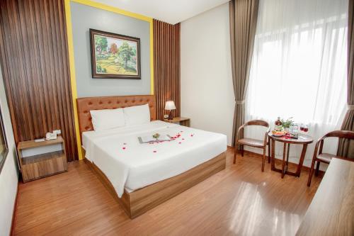 a bedroom with a large white bed and a table at MOMALI Hotel Ninh Binh in Ninh Binh