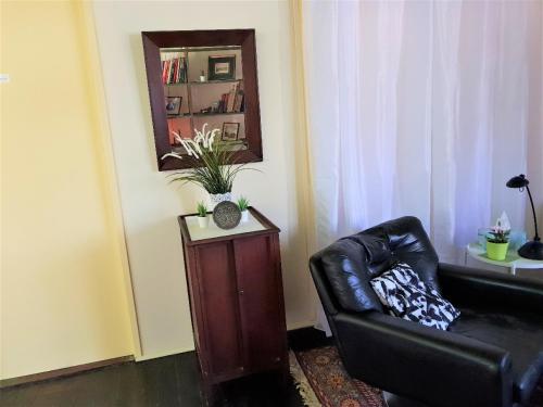 a living room with a black leather chair and a mirror at UNIQUE 1920's Historic Retreat! Pet Friendly! in Springwood