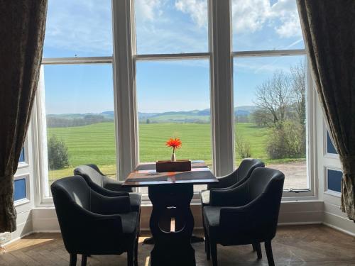 a dining room with a table and chairs and a large window at Ernespie House Hotel in Castle Douglas