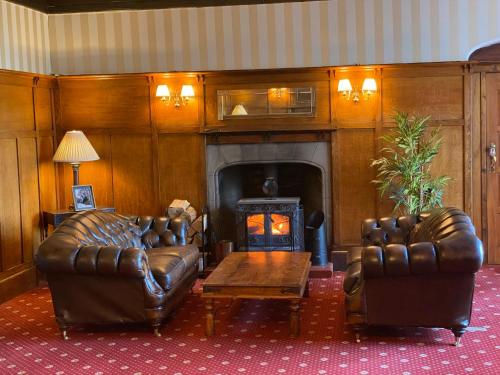 a living room with two leather couches and a fireplace at Ernespie House Hotel in Castle Douglas