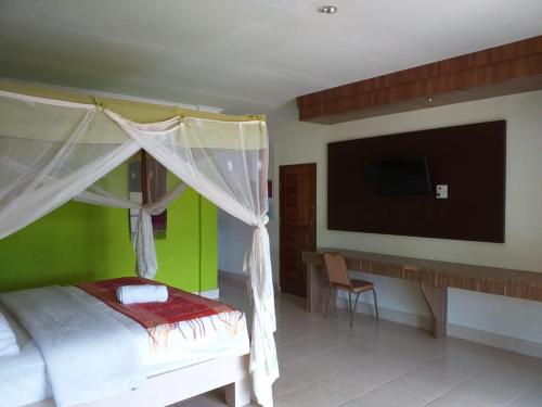a bedroom with a bed and a desk and a television at Toba Village Inn in Tuk Tuk