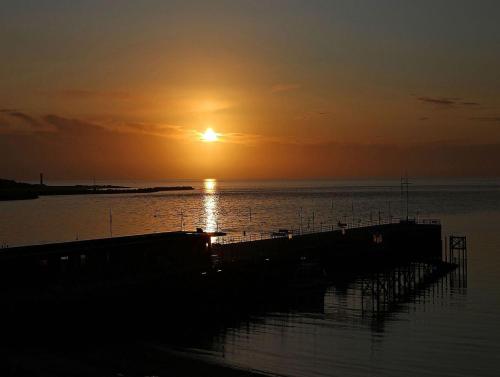 a sunset over a body of water with a dock at Rungholt in Helgoland