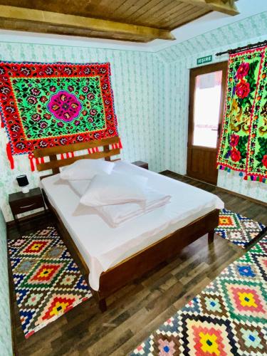a bedroom with a bed and two rugs at Floare de Maramures 1 in Vadu Izei