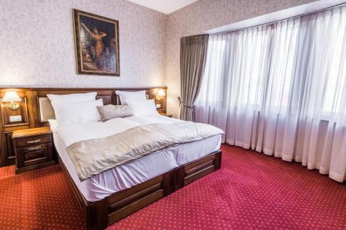 a bedroom with a large bed and a large window at Noblesse Boutique Resort in Sibiu