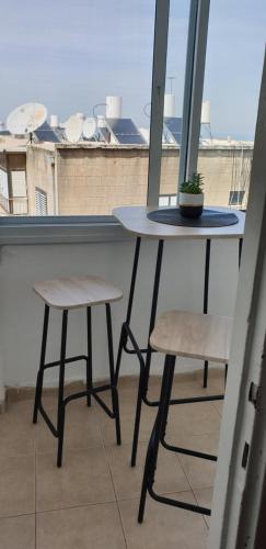 een tafel en twee krukken voor een raam bij Family house bahai gardens in Haifa