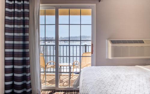a bedroom with a bed and a balcony with a view at Holiday Inn Express Le Claire Riverfront-Davenport, an IHG Hotel in Le Claire