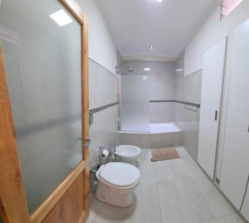Un baño blanco con inodoro y ducha. en Casa Maragata, en Carmen de Patagones