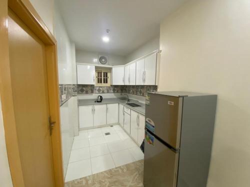 a kitchen with white cabinets and a stainless steel refrigerator at لحظة الاحلام للشقق الفندقية in Makkah