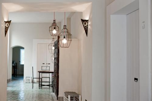 a hallway with white walls and a table and lights at La Casa Dell'Arancio in Favignana