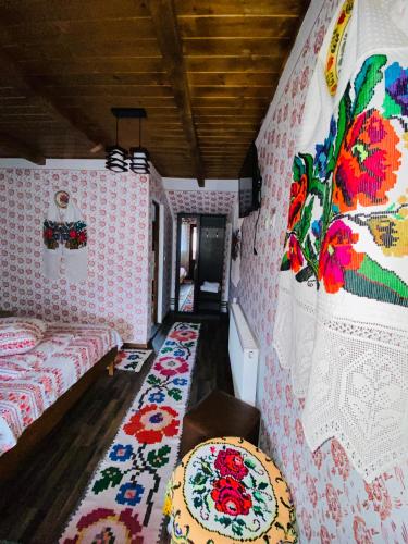 a room with two beds and a wall covered in wallpaper at Floare de Maramures 1 in Vadu Izei