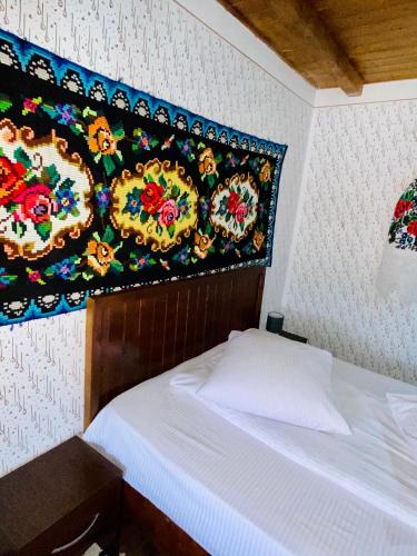 a bedroom with a bed with a tapestry on the wall at Floare de Maramures 1 in Vadu Izei