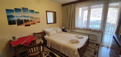 Schlafzimmer mit einem Bett, einem Tisch und einem Fenster in der Unterkunft Луксозно студио в Банско - малко кътче от рая. in Bansko