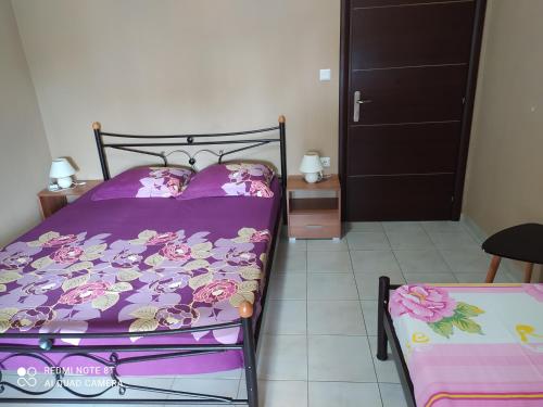 ein Schlafzimmer mit einem Bett mit einer lila Bettdecke in der Unterkunft Giorgos Garden House in Keramotí