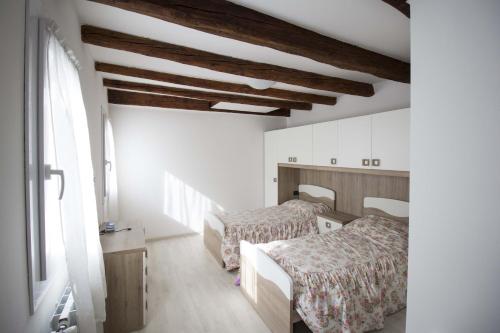 two beds in a room with white walls and wooden ceilings at Dimora Marchiada -apeliving- Pellestrina Ve in Pellestrina