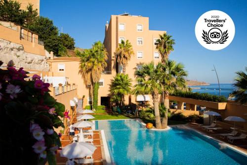 a swimming pool with umbrellas and a hotel at Hotel Punta Nord Est in Castellammare del Golfo