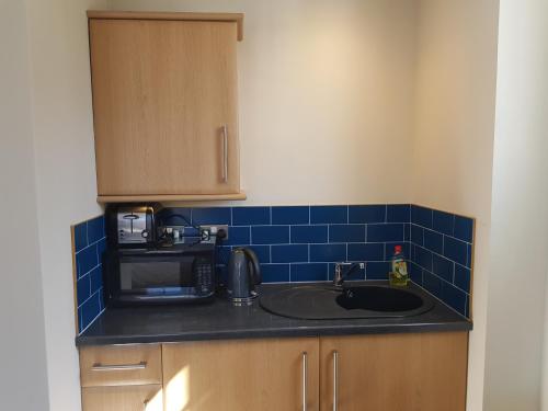 encimera de cocina con fregadero y microondas en Limes Apartments, en Haywards Heath