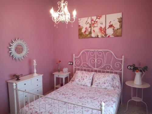 a pink bedroom with a bed and a chandelier at Casa La Liebrecilla in Ríogordo
