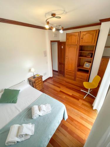 a bedroom with a bed and a chair and wooden floors at Canary Bio Hostel Tenerife in Los Realejos
