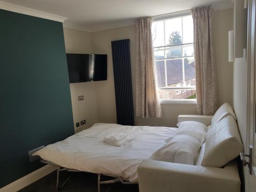 a bedroom with a bed and a couch and a window at Limes Apartments in Haywards Heath