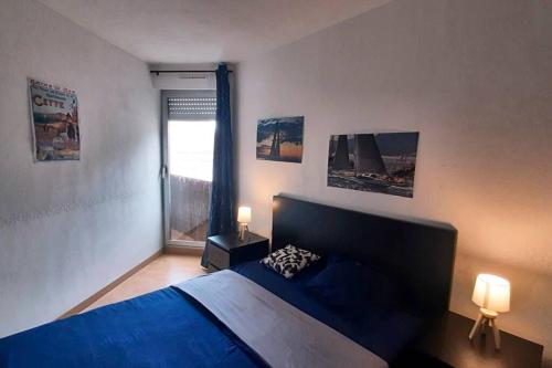 une chambre avec un lit bleu et une fenêtre dans l'établissement Plein coeur Plein soleil, à Sète