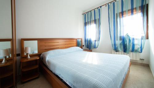 1 dormitorio con 1 cama y 2 ventanas con cortinas azules en Dimora Laguna en Pellestrina