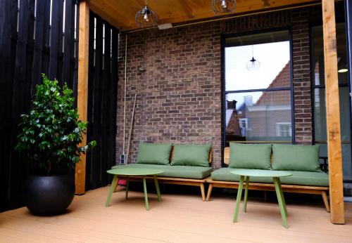 a patio with two green benches and a table at Pink Flamingo Boutique Hostel in The Hague