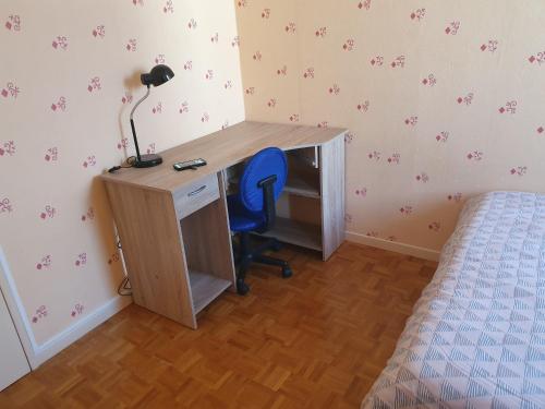 a desk with a blue chair next to a bed at Dans grand appart de 113m2 proche Paris in Creil