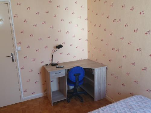 a desk with a blue chair next to a desk with a lamp at Dans grand appart de 113m2 proche Paris in Creil