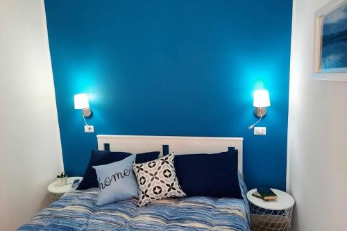 een blauwe slaapkamer met een bed met 2 tafels bij Meli's House in Vibo Valentia