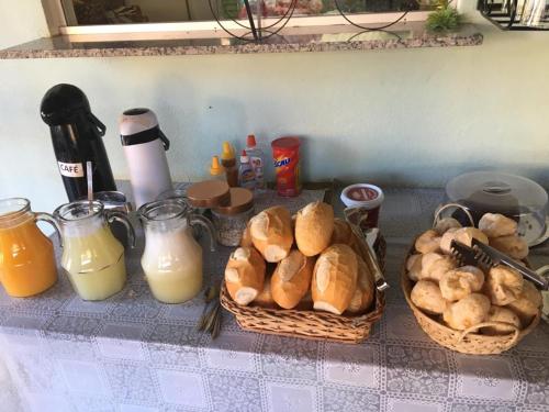 a counter with baskets of bread and bottles of orange juice at Pousada Nova Estrela da Canastra in Delfinópolis