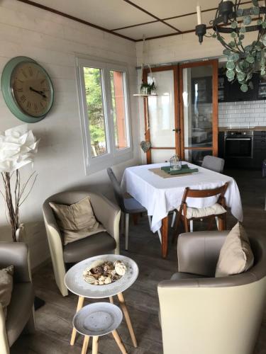 een woonkamer met een tafel en stoelen en een klok bij un ptit chalet in Les Brenets