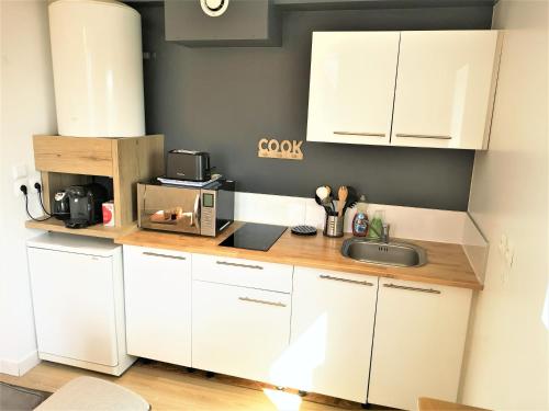 una cocina con armarios blancos y fregadero en Le Renommé Soissons par Picardie Homes, en Soissons