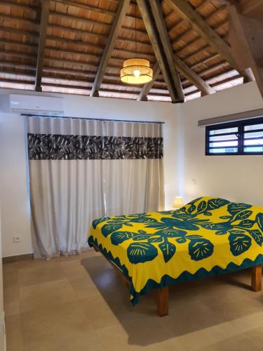 a bedroom with a bed with a yellow and green blanket at Moorea Lodge in Temae