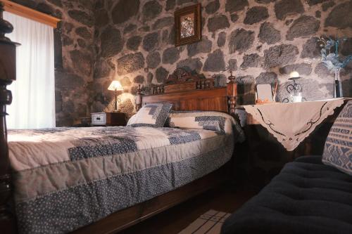 a bedroom with a bed and a stone wall at Baía de Canas Villa in São Roque do Pico
