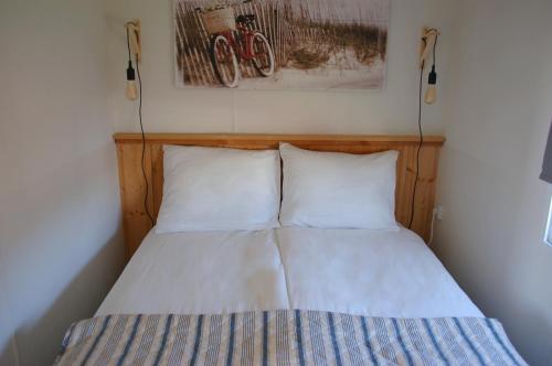 un letto con due cuscini e una foto sul muro di Chalet Wiron aan het Wad. a Westerland