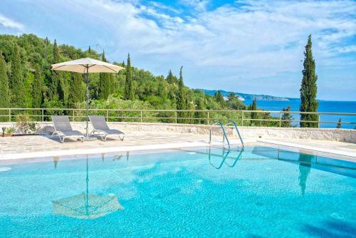 a swimming pool with two chairs and an umbrella at Paleopetres K-Nine - Premium Suite - Kalami - in Kalami