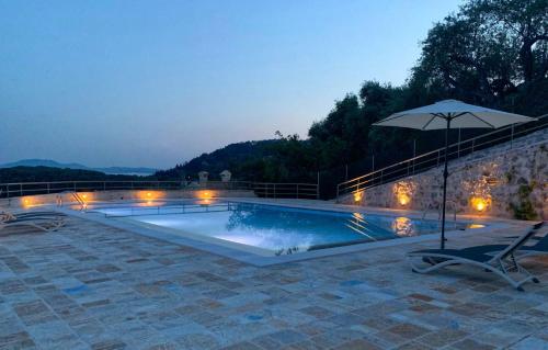 a swimming pool with an umbrella and a chair at Paleopetres K-Nine - Premium Suite - Kalami - in Kalami