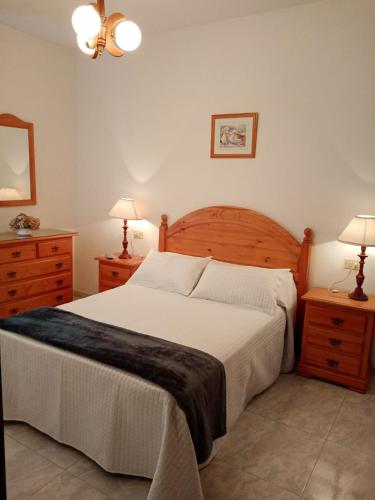 a bedroom with a bed and two dressers and two lamps at Apartamento A Canteira in O Grove