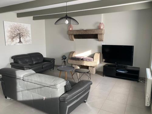 a living room with leather furniture and a flat screen tv at La Petite Maison in Saint-Nicolas-du-Pélem