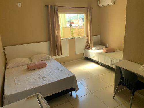 a bedroom with two beds and a window at Hotel JK Buenópolis in Buenópolis