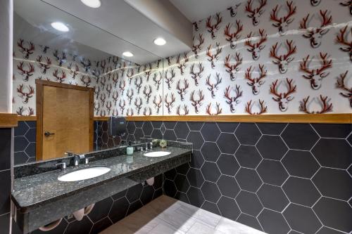 a bathroom with two sinks and a patterned wall at The Bivvi Hostel Telluride in Telluride