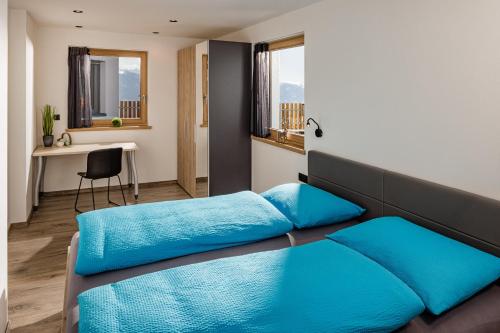 a bedroom with a bed with blue sheets and a desk at Sweet Dolomiti Sonneck in Maranza