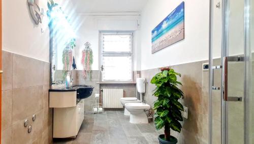 a bathroom with a toilet and a sink and a plant at Guest Holiday Piave 1 in Reggio Emilia