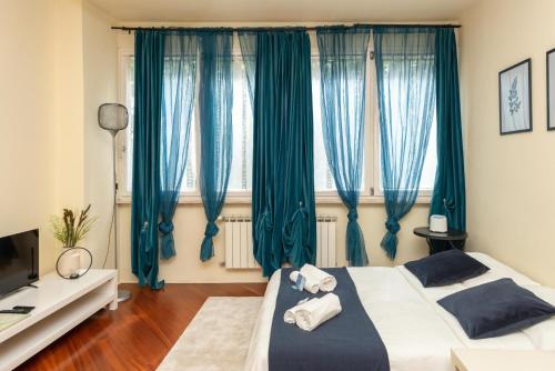 1 dormitorio con 2 camas y cortinas azules en [PISA STAZIONE - CENTRO] Appartamento Elegante con Netflix, en Pisa