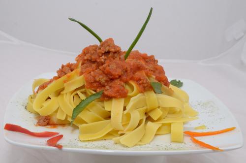 a plate of pasta with meat sauce and vegetables at Golden Inca Hotel in Cusco
